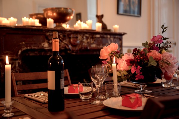 Up close detail of roses pink flowers cutlery on table candles lit and wine bottle red